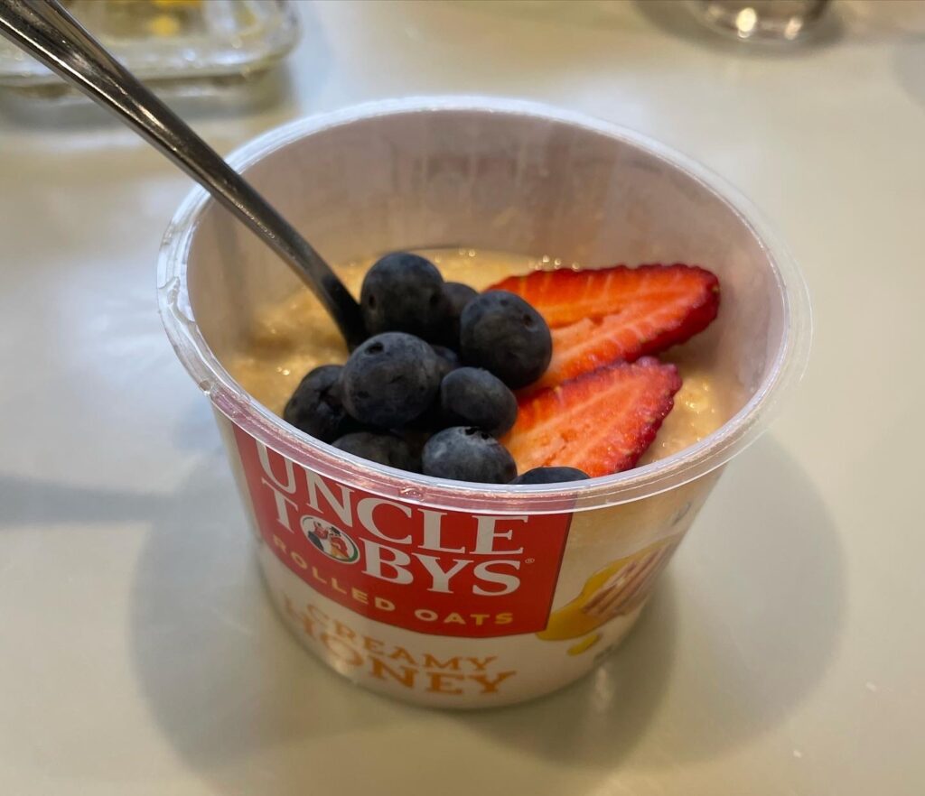Cup of rolled oats with blueberries and two strawberries.