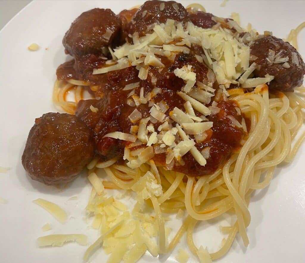 Red sauced meatballs with pasta on plate.