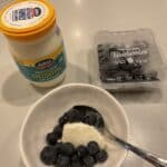 Blueberries in bowl with spoon of yoghurt