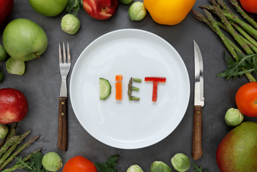 Plate with veggies on it cut up to make the word: Diet.