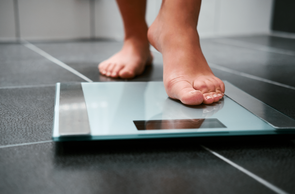 Woman stepping onto a weight scale.