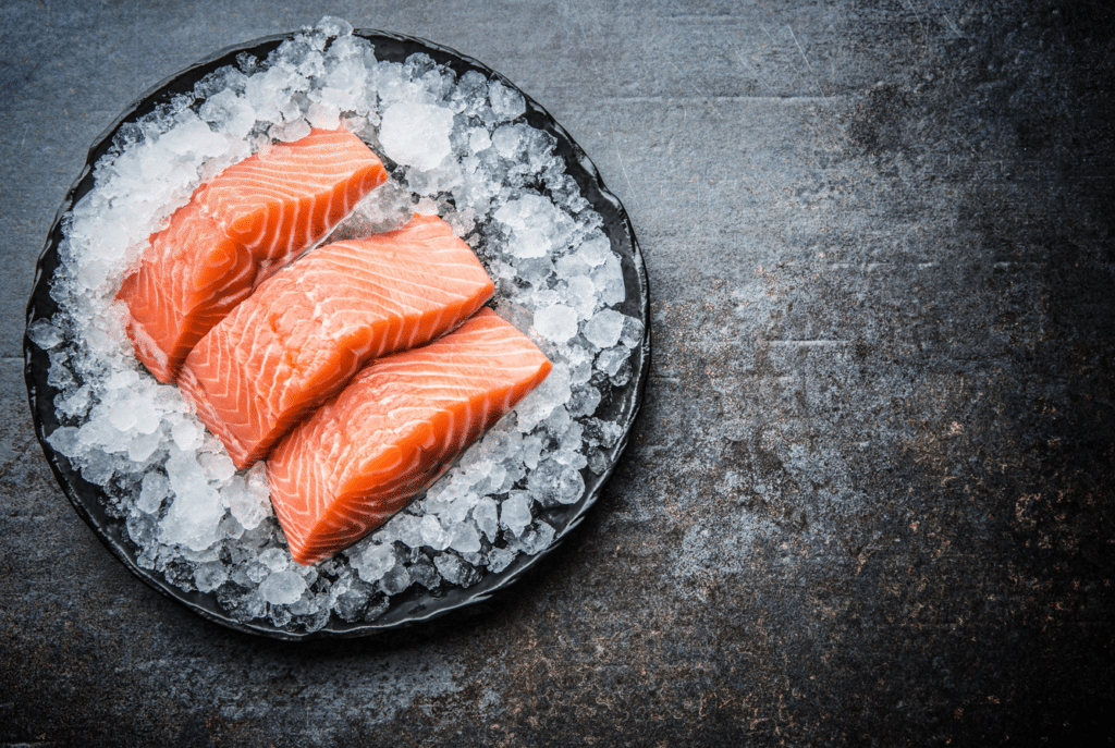 Salmon with ice on a black plate.