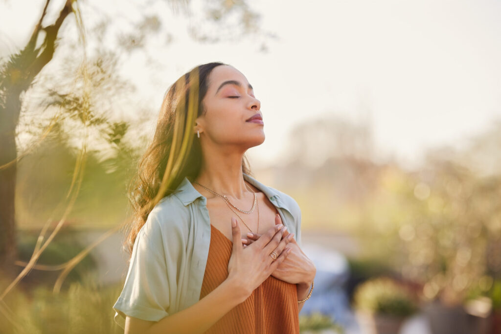 Woman relaxing and working on her breathwork outside.