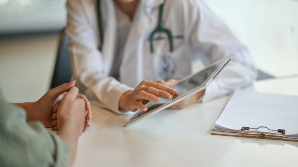 Doctor showing her patient the clinic's prices on a tablet.